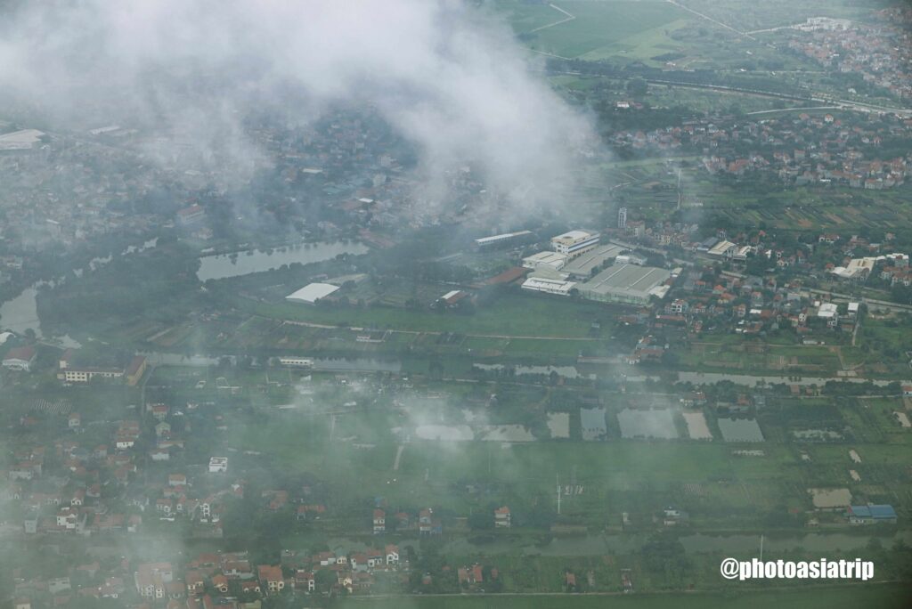 비행기 창문 너머로 보이는 하노이 외곽의 푸른 논과 마을 풍경