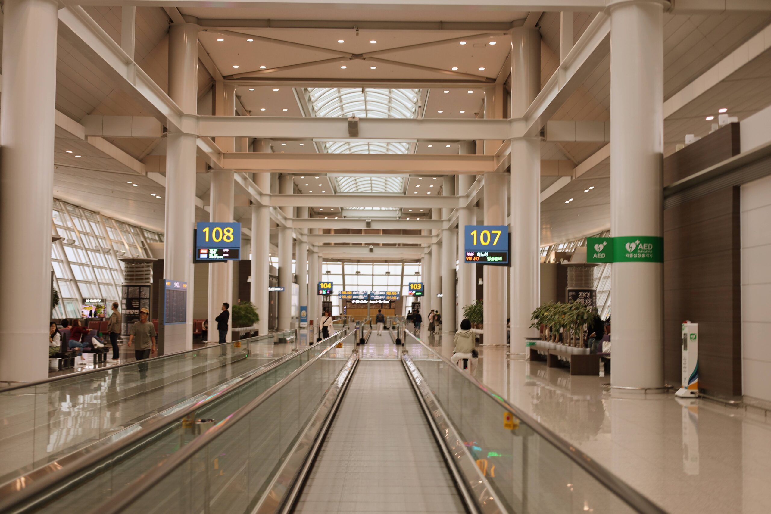 탑승 게이트로 향하는 긴 무빙워크와 공항 내부의 현대적인 모습