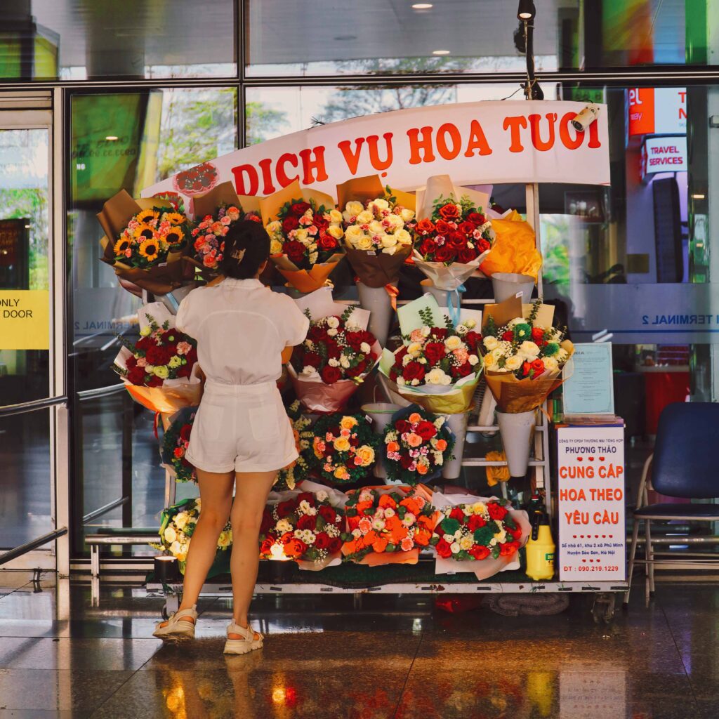 하노이 공항에 있는 작은 꽃 가게. 한 여성이 아름다운 꽃다발을 고르고 있다.