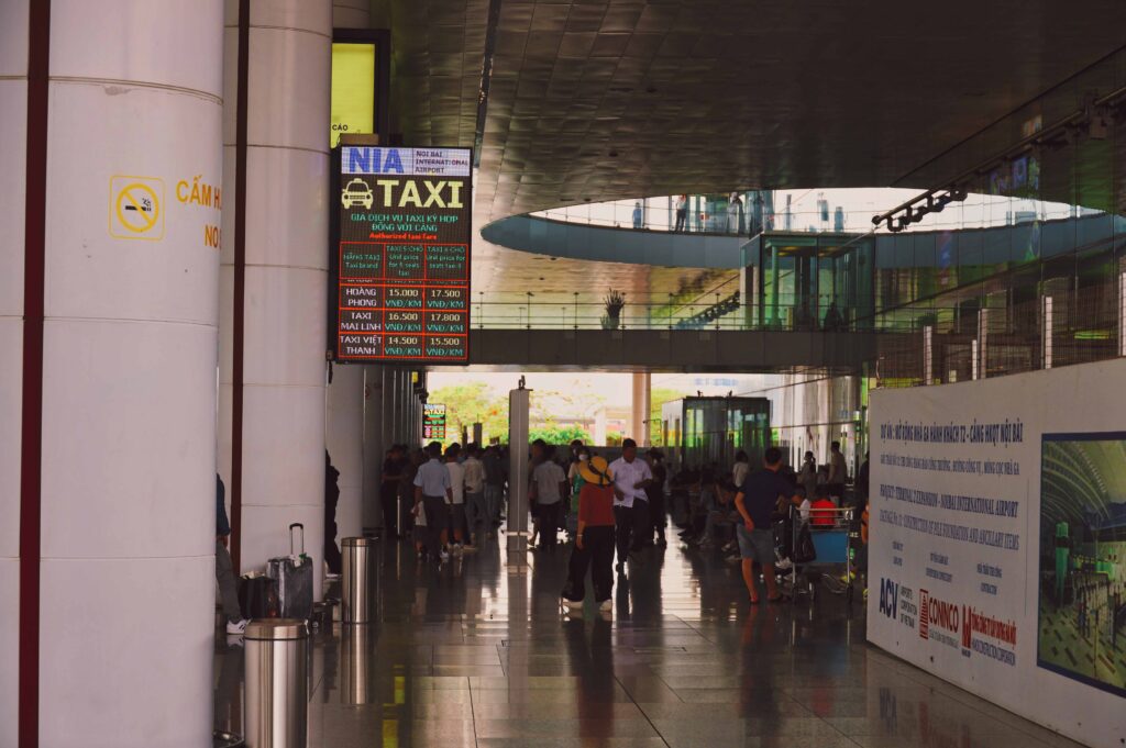 택시 승강장 안내 전광판과 밖으로 나가는 사람들로 붐비는 하노이 공항