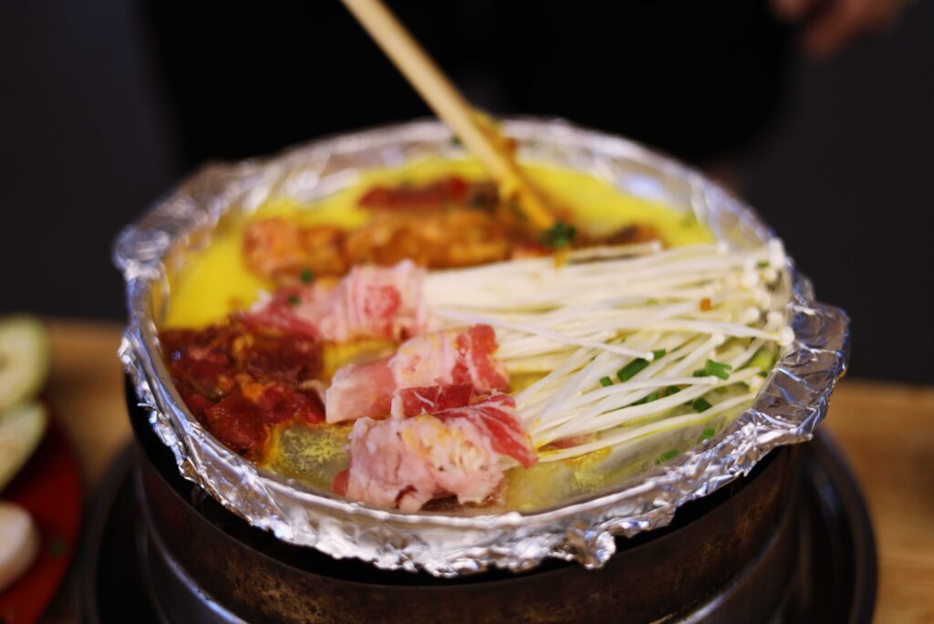 치즈 소스와 고기, 팽이버섯이 올라간 뜨거운 팬 안주